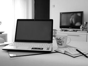 Homeoffice Laptop Tisch TV Kaffetasse schwarz-weiß