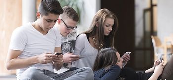 Jugendliche auf dem Boden mit Smartphones von der Seite