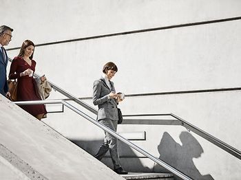 Male and female coworkers moving down on steps. Professionals are