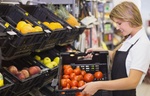 Junge Erwachsene Mitarbeiterin die im Supermarkt Waren einräumt