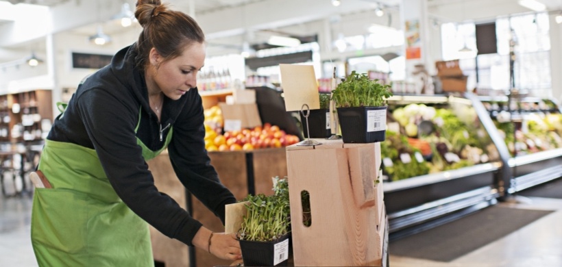 Junge erwachsene Mitarbeiterin sortiert Waren im Supermarkt