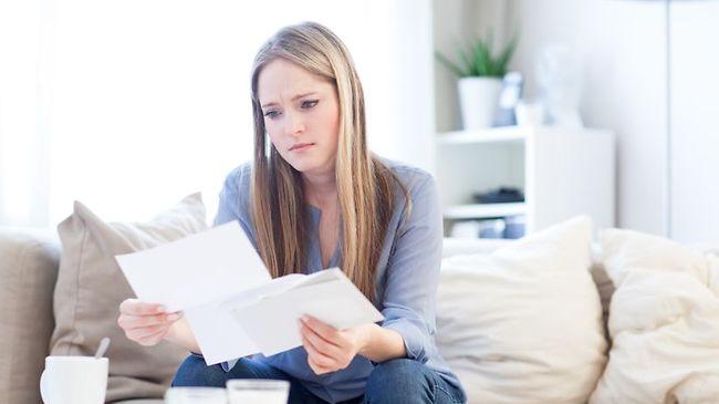 junge Frau blickt besorgt auf Briefe