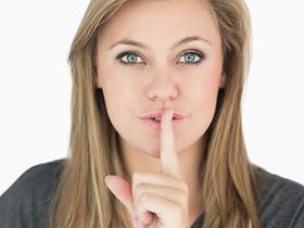 junge Frau hält sich Finger vor den Mund