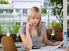 Junge Frau kontrolliert zu Hause Rechnungen