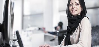 junge Frau mit Kopftuch arbeitet an Desktop