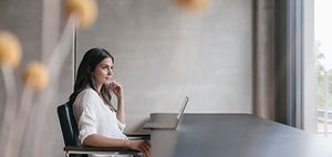 Junge Frau nachdenklich am Laptop