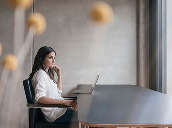 Junge Frau nachdenklich am Laptop