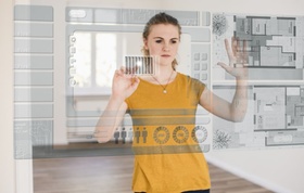 junge Frau organisiert Hausmodell an virtuellem Touchscreen