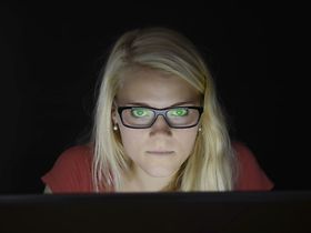 junge Frau starrt im Dunkeln vor Laptop