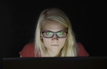 junge Frau starrt im Dunkeln vor Laptop