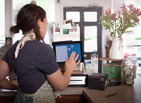 Junge Frau tippt etwas in elektronische Kasse ein