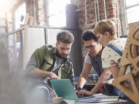 Designers working at laptop in workshop