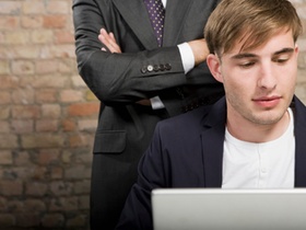 Junger Mann am Laptop, Mann steht dahinter