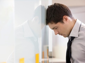 Junger Mann lehnt mit Stirn am Schrank, Augen zu, Stress