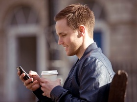 Junger Mann mit Smartphone und Kaffee