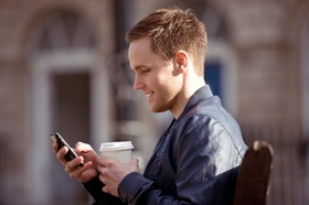 Junger Mann mit Smartphone und Kaffee