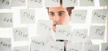 Junger Mann schaut auf Glaswand voller post its