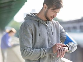 junger Mann schaut beim Sport auf Uhr