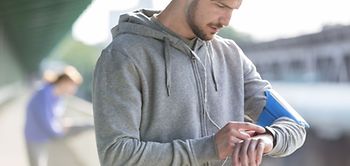 junger Mann schaut beim Sport auf Uhr