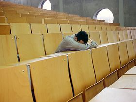Junger Mann schläft gelangweilt in Hörsaal