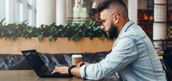 Junger Mann schreibt am Laptop mit