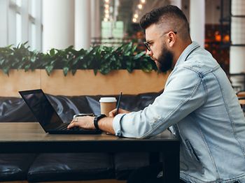 Junger Mann schreibt am Laptop mit