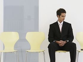 junger Mann sitzt, neben ihm leere Stühle