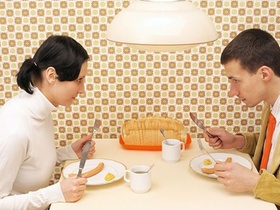 Junger Mann und junge Frau sitzen am Tisch und essen