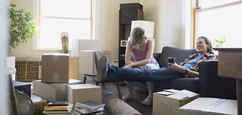 Junges Paar auf Couch sitzend und umgeben von Umzugskartons