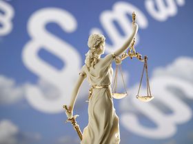 Justitia-Figur vor Paragraphenzeichen