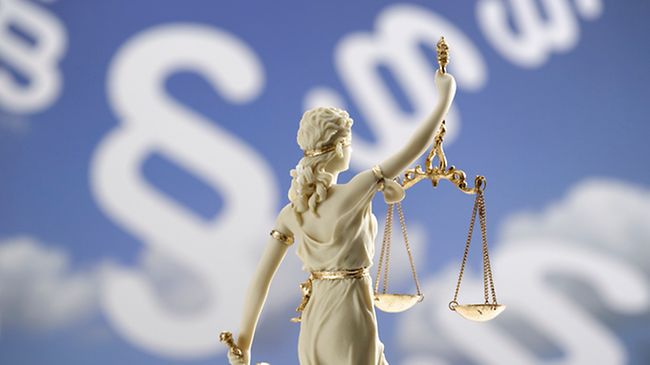 Justitia-Figur vor Paragraphenzeichen