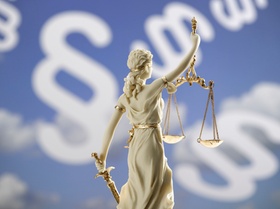Justitia-Figur vor Paragraphenzeichen