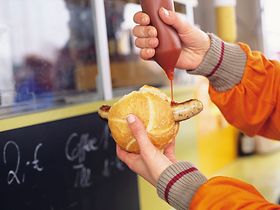 Ketchup wird auf Bratwurstsemmel gegeben, Detail