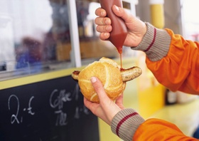 Ketchup wird auf Bratwurstsemmel gegeben, Detail
