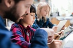 Kind liest mit Betreuung/Lehrer auf Tablet