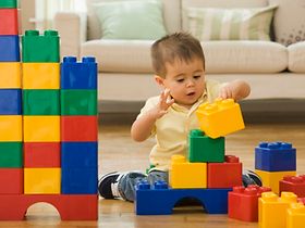 Kind spielt mit bunten Plastiksteinen