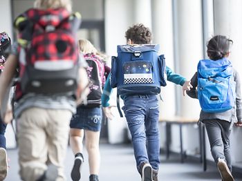 Kinder rennen in die Schule