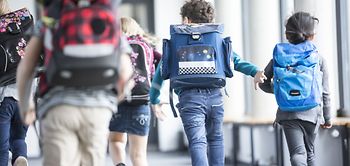 Kinder rennen in die Schule