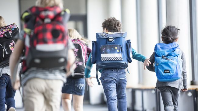Kinder rennen in die Schule