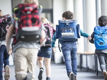 Kinder rennen in die Schule
