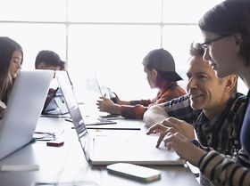 Klasse arbeitet zusammen mit Lehrer an Laptops