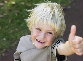 Kleiner Junge zeigt fröhlich Daumen hoch
