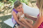 Kleines Mädchen bekommt von erwachsener Person ein Pflaster auf verletztes Knie geklebt