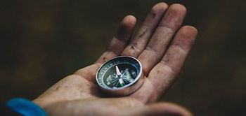 Kompass auf dreckiger Hand