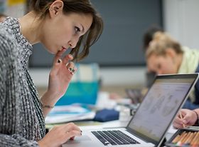 Konzentriert aussehende Studentin arbeitet an Laptop
