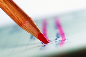 Close Up of a Red Colouring Pencil Crossing Out Handwriting on a Piece of Paper