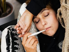 Kranke Frau mit Fieberthermometer im Mund
