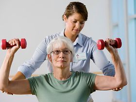Krankengymnastik, Therapeutin und ältere Frau mit Hanteln