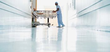 Krankenhaus_Pfleger schiebt Patient durch Flur