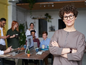 Lächelnde Frau mit verschränkten Armen vor Kollegen